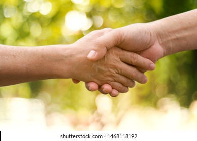 Closeup of people holding hands on a green bokeh background.