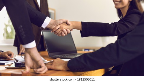 Closeup Of People Shaking Hands Above Office Desk Making Successful Business Deal. Happy Company Worker And Satisfied Client Confirm Agreement With Handshake. Customer Thanks Bank Adviser For Help