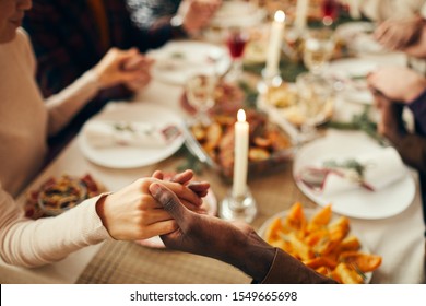 Closeup Of People Sitting At Dining Table On Christmas And Joining Hands In Prayer, Copy Space