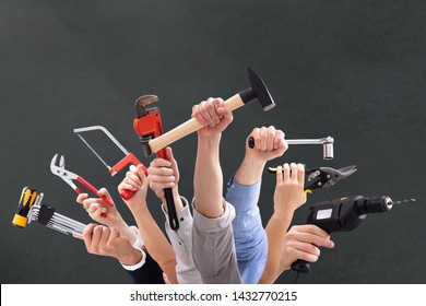 Close-up Of People's Hand Holding Carpentry Tools Against Black Background