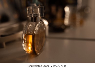 close-up of perfume bottle on a dresser in dim lighting with sun glowing through the glass - Powered by Shutterstock