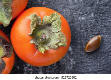 Closeup Persimmon With Seeds On Dark Backdrop. Top View. Healthy Tropical Fruits.