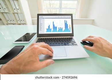 Close-up Of A Person Analyzing Graph On Laptop In Office