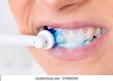 Close-up Of A Person Brushing Teeth Using Electric Toothbrush