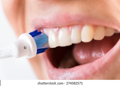 Close-up Of A Person Brushing Teeth Using Electric Toothbrush