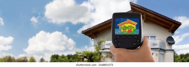 Close-up Of Person Detecting Heat Loss Outside House Using Infrared Thermal Camera