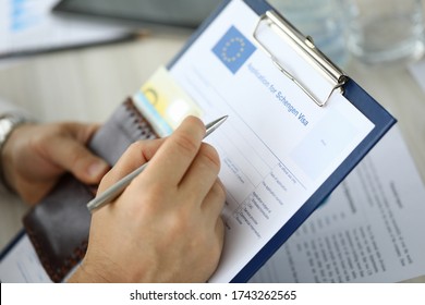Close-up of person filling application form for schengen visa on clipboard. Man holding silver pen. Writing personal information on paper. Travelling abroad or immigration concept - Shutterstock ID 1743262565
