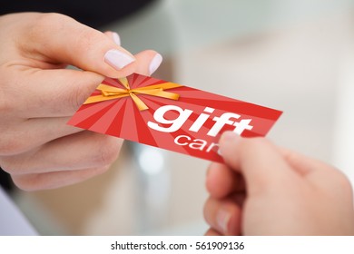 Close-up Of Person Hand Giving Gift Card To Another Person