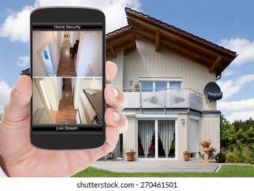 Close-up Of Person Hand Holding Mobile Phone With Home Security System