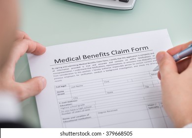 Close-up Of Person Hand Over Medical Benefits Claim Form