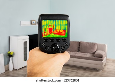 Close-up Of Person Hand Using Infrared Thermal Camera In Living Room At Home