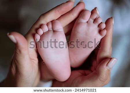 Close-Up of Person Holding Babys Feet, Cherishing Precious Moments. A tender moment captured in a close-up photo of a person cradling a babys tiny feet with love and care.