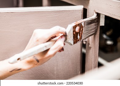 Closeup Of Person Holding Paint Brush And Painting Kitchen Cabinets