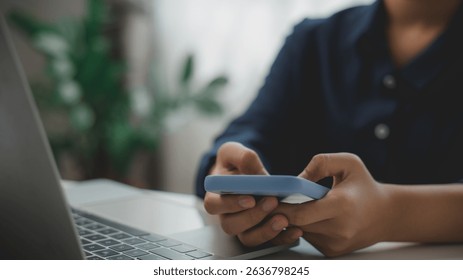 Close-up of person holding smartphone in front of laptop, representing mobile communication, digital lifestyle, multitasking, remote work, and smart connectivity in modern work environments. - Powered by Shutterstock - Get 15% off with code: PIKWIZARD15