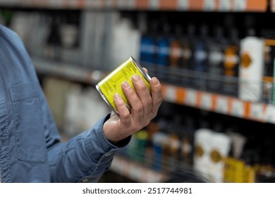 Close-up of person inspecting can in grocery store. Focus on nutritional information reflects importance of informed shopping choices and healthy living. Ambient shelves display additional products. - Powered by Shutterstock