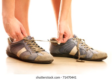 A Close-up Of A Person Lacing Up Too Big Shoes Over White Background