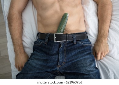 Close-up Of A Person Lying On Bed With A Cucumber Stuffed Down On His Pants