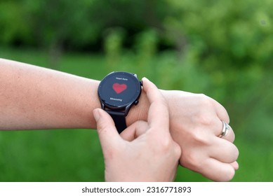 A closeup of a person monitoring heart rate on a smartwatch outdoors