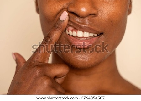 Close-up of a person playfully pulling their upper lip with a finger, revealing teeth and showcasing a playful expression.
