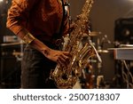 Close-up of person playing saxophone, capturing the energy and focus during performance in recording studio setting with various musical instruments surrounding