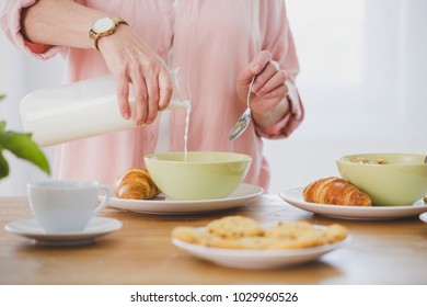 Close-up of a person pouring milk into a bowl on a plate with croissant. Breakfast in the morning - Powered by Shutterstock