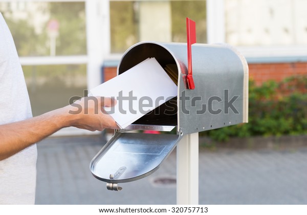 Close-up Of\
Person Putting Stack Of Letters In\
Mailbox