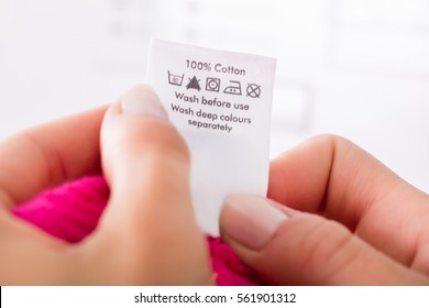 Close-up Of Person Reading The Clothing Label Showing Washing Instructions