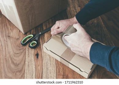 Close-up Of Person Sealing Up Shipping Box With Parcel Tape, Pruchase Return And Return Of Goods Concept