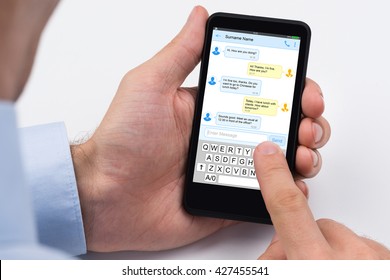 Close-up Of A Person Sending Text Message Using Mobile Phone