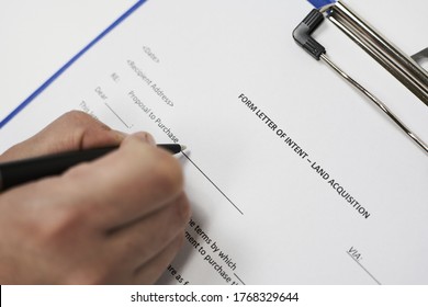 A Closeup Of A Person Signing A Form Letter Of Intent For Land Acquisition