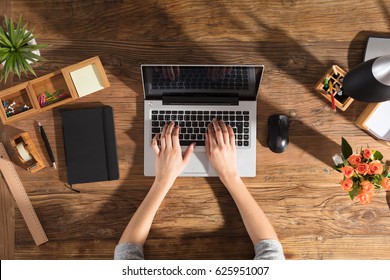 Close-up Of A Person Using Laptop Computer On Office Wooden Desk