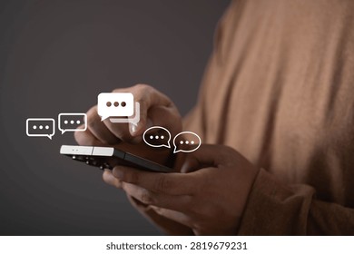 Close-up of a person using a smartphone with virtual chat icons. Concept of online communication, instant messaging, customer support, social networking, digital interaction, and mobile technology.