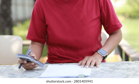 Close-up of a person using a smartphone while reviewing documents at an outdoor workspace. Mobile business management, digital communication, remote work, productivity, and modern office workflow concept.