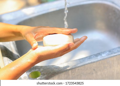 Close-up of a person washing hands with water outdoors.