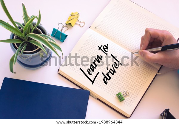 Closeup of a personal agenda\
setting an important date writing with pen. The words Learn to\
Drive written on a white notebook to remind you an important\
appointment.
