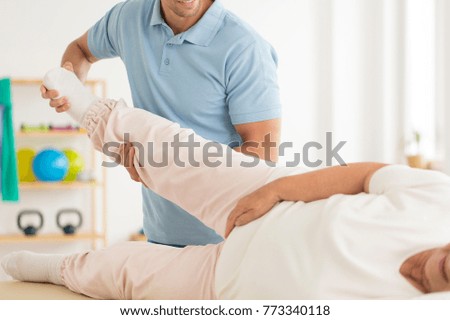 Close-up of personal physiotherapist rehabilitating senior woman's joints after hip reconstruction