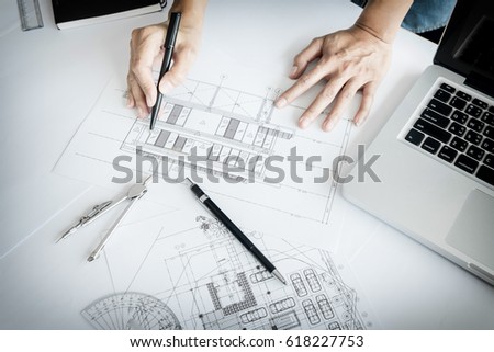 Close-up Of Person's engineer Hand Drawing Plan On Blue Print with architect equipment