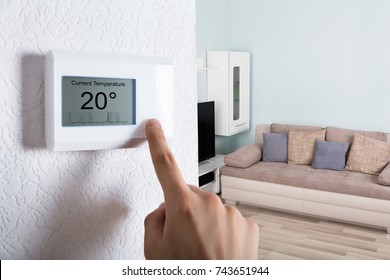 Close-up Of A Person's Hand Adjusting Digital Thermostat At Home