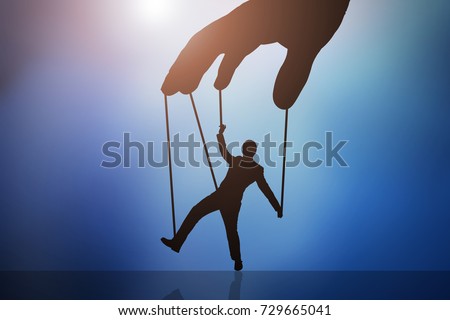 Close-up Of Person's Hand Controlling Puppet Man Against Blue Background