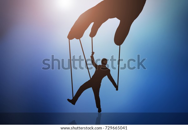 Close-up Of Person\'s Hand Controlling Puppet\
Man Against Blue\
Background