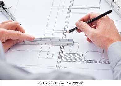 Close-up Of Person's Hand Drawing Plan On Blue Print