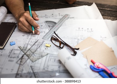 Close-up Of Person's Hand Drawing Plan On Blue Print With Architect Equipment.