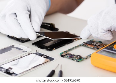 Close-up Of Person's Hand Fixing Damaged Screen On Mobile Phone