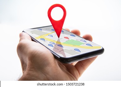Close-up Of A Person's Hand Holding Cellphone With Red Map Pin Pointer Against White Background - Shutterstock ID 1503721238