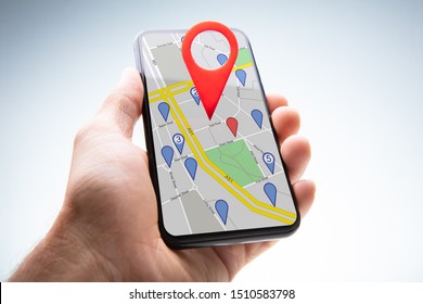 Close-up Of A Person's Hand Holding Cellphone With Red Map Pin Pointer Against White Background
