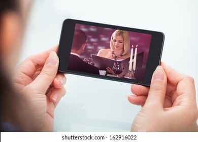 Close-up Of Person's Hand Holding Cellphone Watching Video