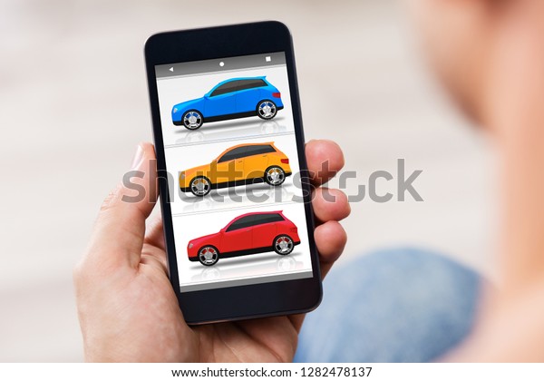Close-up Of A Person\'s Hand Holding Cellphone With\
Colorful Cars On\
Screen