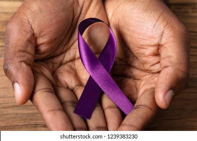 Close-up Of A Person's Hand Holding Ribbon To Support Alzheimer's Disease Awareness