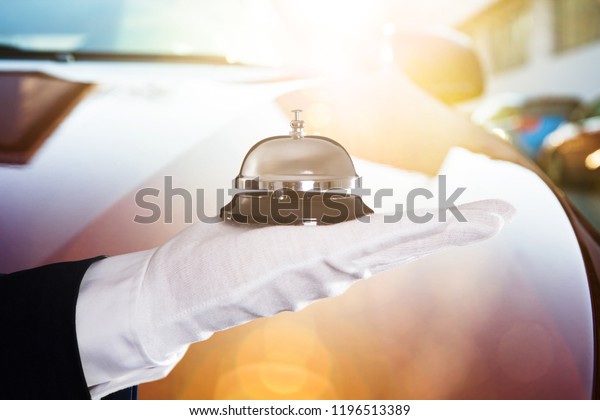 Close-up Of A Person\'s Hand Holding Service Bell In\
Front Of Car