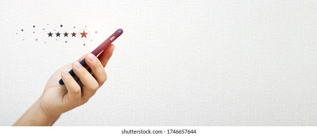 Close-up of a person's hand holding a smartphone with a red five-star feedback icon with the concept of business service and services. The client gives an excellent rating in the online application